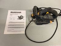 Mastercraft electric hand planer beside its operating manual on a flat surface.