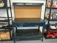 Front view of the Mastercraft workbench showing pegboard with hooks, two drawers, and lower shelf.