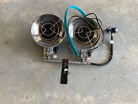 Top-down view of the dual propane heater showing dual stainless steel heating heads, metal protective guards, and the central gas control.