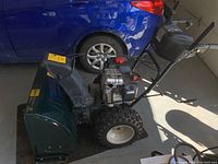 Side view showing auger housing, engine, tires and handle controls