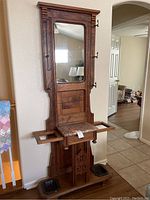 Full front view of walnut hall tree showing mirror, hooks, marble shelf, drawer and base with drip trays
