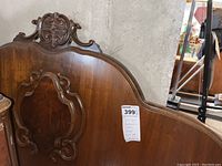 Front and partial side view of antique full size wooden headboard showing carved decorative details and polished finish.