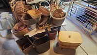 Wide shot of many assorted woven baskets in various sizes and shapes stacked on and around a table.