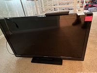 Magnavox flatscreen TV showing the front side and base stand on carpeted floor.