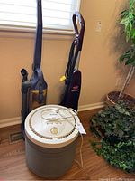 Three cleaning appliances including Kenmore HEPA air filter, Bissell Quick Steamer carpet cleaner, and Eureka vacuum cleaner, all standing on wood floor near a window and plant.