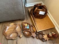 Photo showing monkey pod wood scalloped salad bowls, wooden divided serving bowl, wooden trays, decorative wooden pieces, and small colored candles.