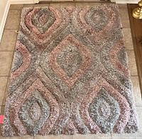 Small rug featuring diamond pattern in blush and gray tones, plush pile