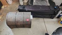 Small wooden trunk with curved top and metal bands from angled side view, displaying surface wear.