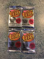Four sealed packs of 1992 Fleer Ultra football trading cards with silver foil packaging featuring '92 Fleer Ultra logo and text about Reggie White and Chris Miller.