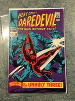 Front cover of Daredevil #39 comic featuring Daredevil swinging with baton against purple background.