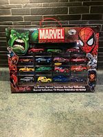 Front view of Marvel Maisto 15-piece die-cast car set packaging showing Hulk, Spider-Man, and Captain America graphics with all cars visible in the box.