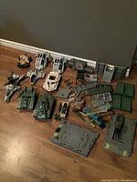 Top-down photo showing an array of vintage GI Joe vehicles and playset parts arranged on a wooden floor.