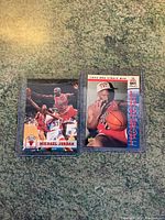 Two Michael Jordan 1993 NBA Finals basketball cards displayed side by side on a mottled surface, each in protective sleeves.