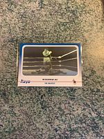 Muhammad Ali hologram card showing Ali standing in ring over opponent downed on the canvas