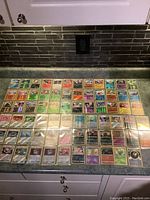 Full view of forty-eight Pokémon holographic cards displayed on a counter, arranged in six rows and eight columns, showing a mix of Pokémon types and energy cards.
