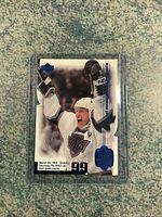 Front of Wayne Gretzky hockey card in a clear plastic case, showing the player celebrating in white gear with text and logos.