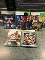 Photo showing all five Xbox 360 game cases arranged on floor with visible artwork and titles.