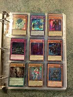 First page of binder showing nine Yu-Gi-Oh cards in plastic sleeves including monster and spell cards, some holographic.