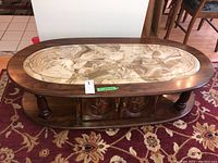 Top view of the oval wooden coffee table showing the marble inset top and carved wooden doors beneath.