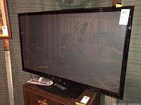 Full front view of the LG 50-inch television on a wooden stand with reflection on screen.