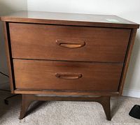 Front-facing view of the wooden bedside table showing two drawers with curved handles and tapered legs.