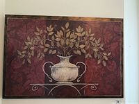 Front view of canvas print featuring a white vase with golden leaves on a red patterned background mounted in a wood frame.