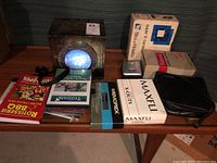 Wide view of lot items on a low table showing Stargate model box, camera, film tapes, poster, and packaging