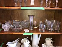 Shelf with clear glass tumblers and bowls, various sizes and designs.
