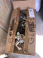 Open cardboard box containing numerous vintage Olympic glassware pieces wrapped and unwrapped with some visible Olympic designs.