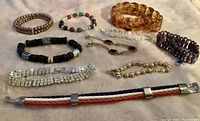 Photo of 10 assorted bracelets on fabric background showing various stretch, beaded, linked, rhinestone, and woven designs.