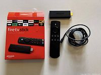 Top view of the orange and white box packaging, Alexa Voice Remote, Fire TV Stick, and USB power cable all laid out on a flat surface.