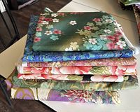 Folded Asian printed quilting fabrics stacked showing different colorful floral and geometric designs
