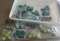 Various beads in different shapes and colors displayed in plastic bags and a white tray