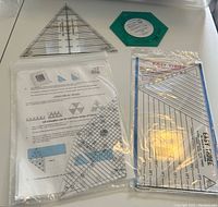 Cutting templates and rulers arranged on a white surface including large and small triangular rulers, a rectangular ruler labeled 'Easy Three', a green octagonal template, and an instruction sheet.