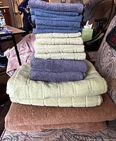 Stack of bath towels and bath sheets in blue, cream, brown, and grey, showing texture and sizes