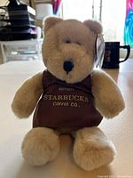 Front view of tan Starbucks Bearista Bear with brown apron embroidered with Starbucks Coffee Co. text.