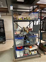Front view of two connected metal shelving units filled with various storage boxes and tools, on wheels.