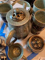 Top view of coffee pot lid, cups, and sugar bowl showing jade green crackled glaze with gold accents.