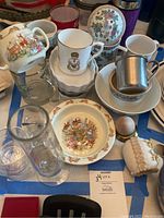 Photo showing assorted china and glass items, with cups featuring bunny motifs and a floral etched glass vase