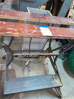 Full angled view of the folding work bench showing entire metal frame, wooden tops with holes and footrest.