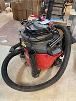 Photo of the front and side view of the red and gray Craftsman 16 gallon shop vac with hose and accessories visible