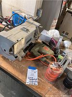 Top view showing bench grinder, electric drill, tools and containers on tabletop.