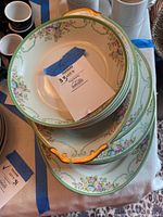 Top view photo showing stack of soup bowls and partially visible plates and platters with tape label