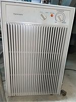 Front view of Kenmore dehumidifier showing vertical grille and control panel with fan and humidistat knobs, and red indicator light.