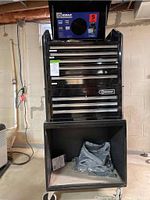 Front overview of entire tool cabinet showing top drawers, middle drawers, open bottom compartment, and portable radio on top