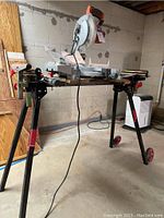 Overall front view of Ridgid miter saw on folding stand in basement workshop