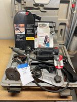 RotoZip spiral saw power tool with cord, straight edge guide, instruction manual, and accessories inside original hard plastic case.