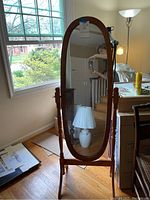 Full image of the oval standing mirror showing the wooden frame, base, and reflective surface.