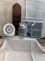 Full lot showing cereal bowls stacked, bread plates stacked, stainless steel dispenser, wooden mail holder, and glass jar arranged on table