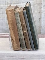 Front view of spines of 5 vintage books showing titles and condition.